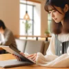 A Japanese student using a tablet or smartphone app for learning in a bright and modern setting, studying diligently with the course content visible on the device. The environment is quiet and conducive to learning.